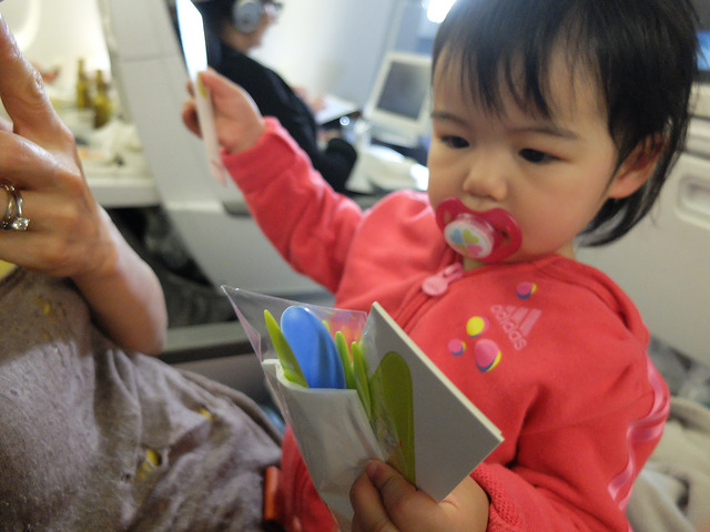 baby playing plastic forks on the plane